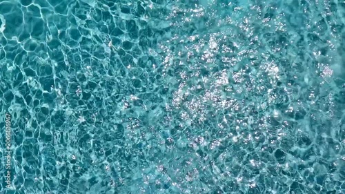 Full frame overhead view of crystal clear turquoise swimming pool water with bright sparkling sun glares and ripples