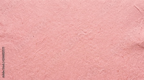 A close-up shot of textured pink paper. The paper has a rough, handmade appearance with visible fibers and slight variations in color.