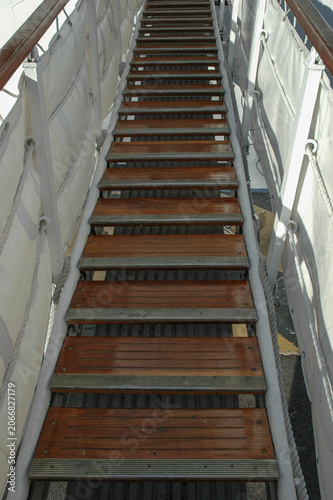 Photography A long wooden gangway gangplank with steps and canvas side barriers leading upwa