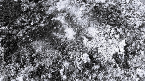Fotografi Black and white close-up of coarse dusty rubble with mixed powder patches, rough granules, and abstract construction texture