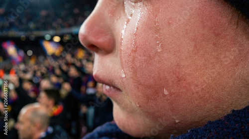 Close-up of Person Crying with Blurred Stadium Crowd Background