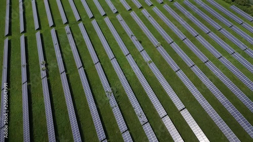 Aerial view shows large solar panels placed in a field. The setup highlights the use of renewable energy. This location focuses on solar power generation for a sustainable future