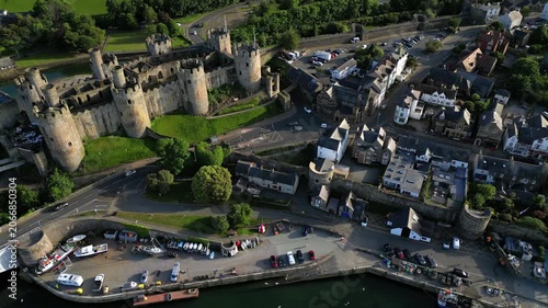 Conwy Castle and the surrounding town. You can see the castle walls and the buildings next to the water. The view captures everyday life in Conwy