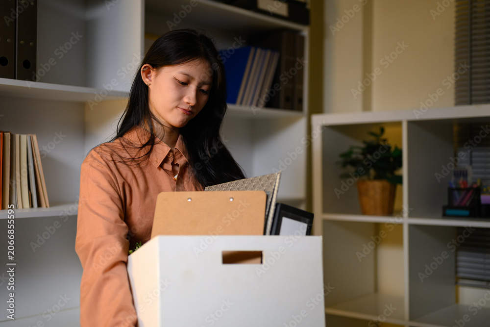 Fototapeta premium Young Asian Businesswoman Packing Personal Belongings in Box After Resignation Leaving Office Job