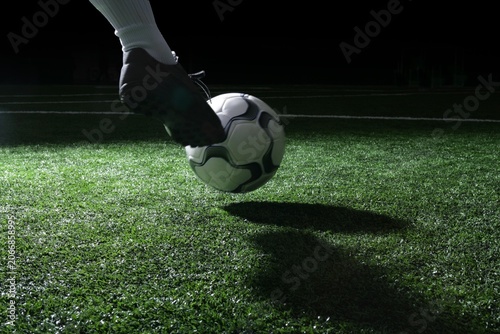 Obraz na plátně Soccer ball being kicked on grass sports field at night with football training c