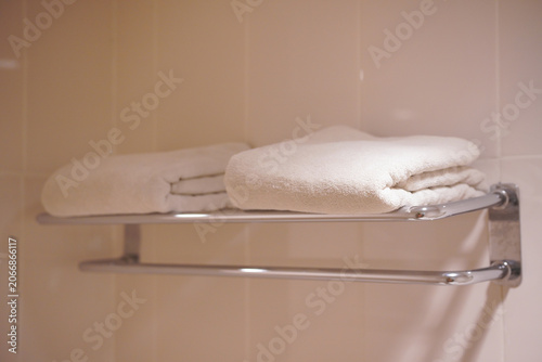 Two folded white cotton towels on a hotel bathroom metal rack. Ideal for hospitality, travel, hygiene, and householdrelated design projects.