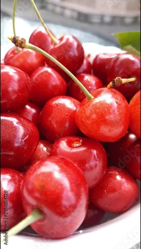 Close-up view of ripe red cherries in a white bowl. Fresh juicy summer fruit showcasing natural sweetness, vibrant color and healthy seasonal nutrition.