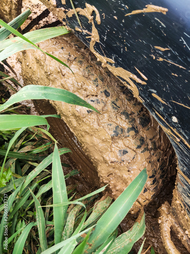 Off road vehicle tire covered in thick mud while navigating challenging hillside trail in Bogor, illustrating rugged adventure, difficult terrain, and extreme driving conditions.