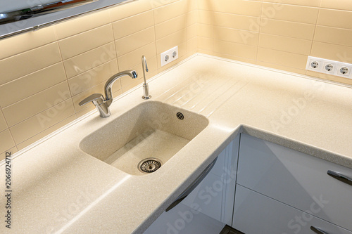 Photos beige integrated stone sink sits in a matching speckled countertop; a polished c