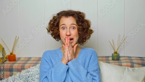 cheerful young woman with curly hair proudly showing her colorful braces and confident smile in a cozy home setting