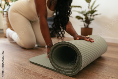Foto Black woman unrolling yoga mat on floor, getting ready for home fitness exercise