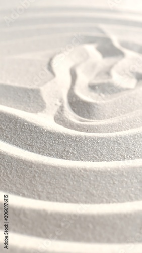 A close-up of a textured, white, sandy surface with intricate, swirling patterns