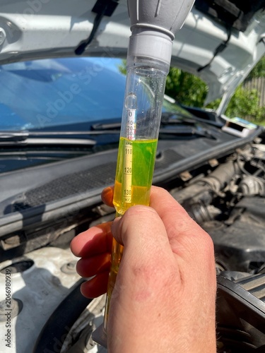 Fotografie Close up of a mechanic checking car coolant density with a hydrometer tester