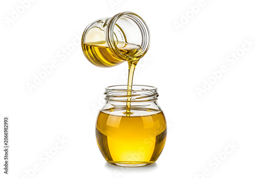 Golden honey dripping from honey dipper into jar.
