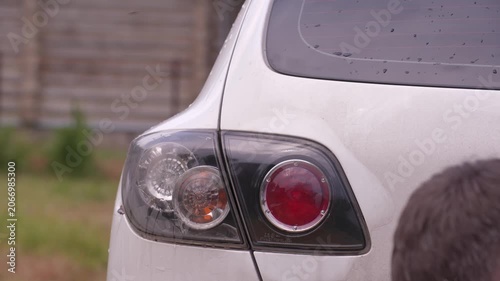 Wash the headlights of a car. A person washes the car's headlights with a sponge.