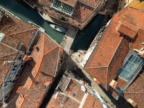 Venetian old city historic district with tiled roofs and narrow canals on sunny day, Venice, Italy
