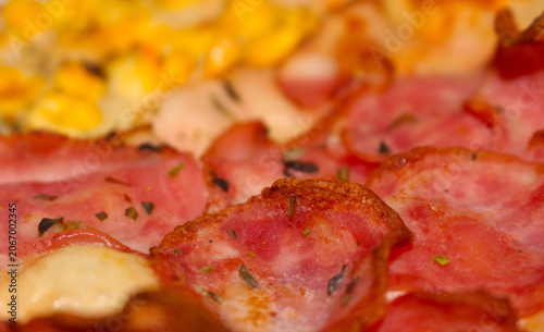 Close up of pizza. Delicious pizza texture with ingredients. Savory pizza details with blurred background. pizza with selective focus. Details of pizza with corn blurred in the background.