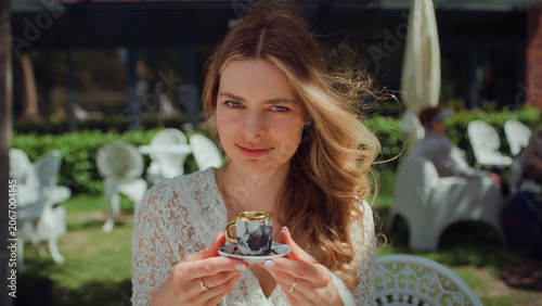 Woman sitting in an outdoor cafe and holding an elegant espresso cup