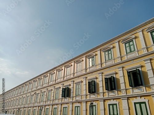 Low angle view of neoclassical yellow building with green shutters