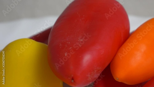 Close-up of fresh red and yellow sweet bell peppers rotating on a white plate, showcasing their smooth texture and vibrant colors under bright studio lighting.