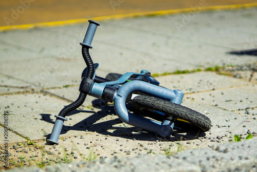 Children's balance bike lying on pavement after outdoor play