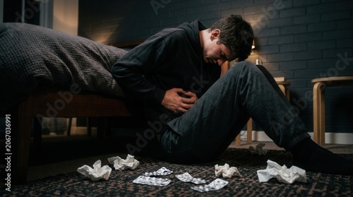 Young Man Feeling Unwell And Experiencing Abdominal Pain At Home