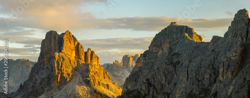 Fotografie Wide aerial panorama of the Dolomites at sunset with dramatic sun rays, rugged mountain formations and expansive alpine scenery