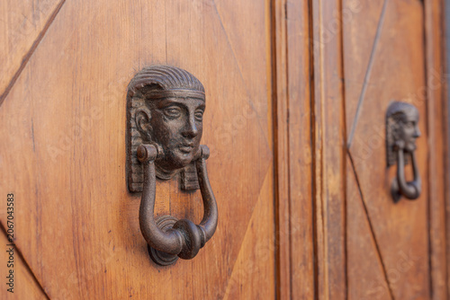 Ornate Egyptian style door knocker on old wooden entrance