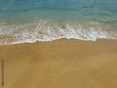 Gentle ocean waves washing ashore on golden sandy beach
