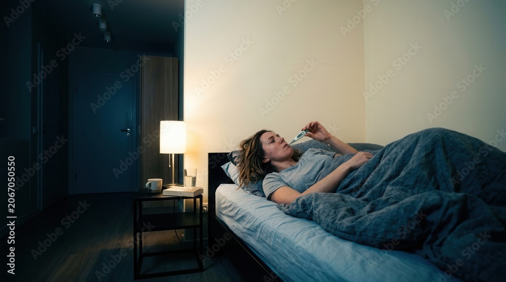 Fototapeta premium Woman In Bed Measuring Temperature Checking For Fever Due To Illness During The Night