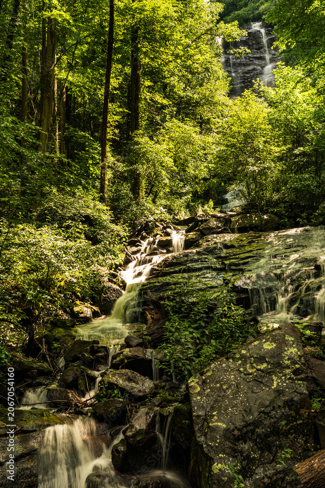 Obraz premium Multi-tiered cascade waterfall flowing through dense green forest at Amicalola Falls State Park, North Georgia mountains, USA.