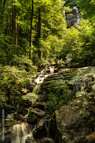 Multi-tiered cascade waterfall flowing through dense green forest at Amicalola Falls State Park, North Georgia mountains, USA.