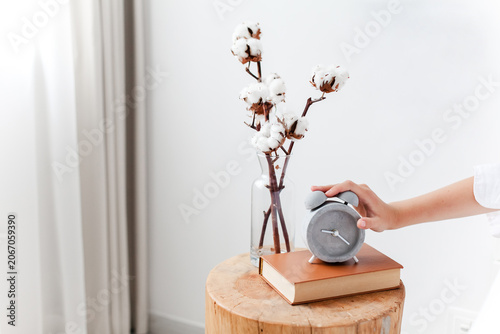 Foto Woman turning off an alarm clock on bedside table in cozy bedroom interior