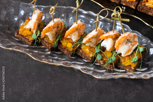 Shrimp appetizers on a long plate with brown bread and toppings for a gathering or event