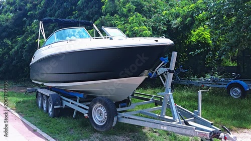 Boat on trailer parked in green outdoor setting  