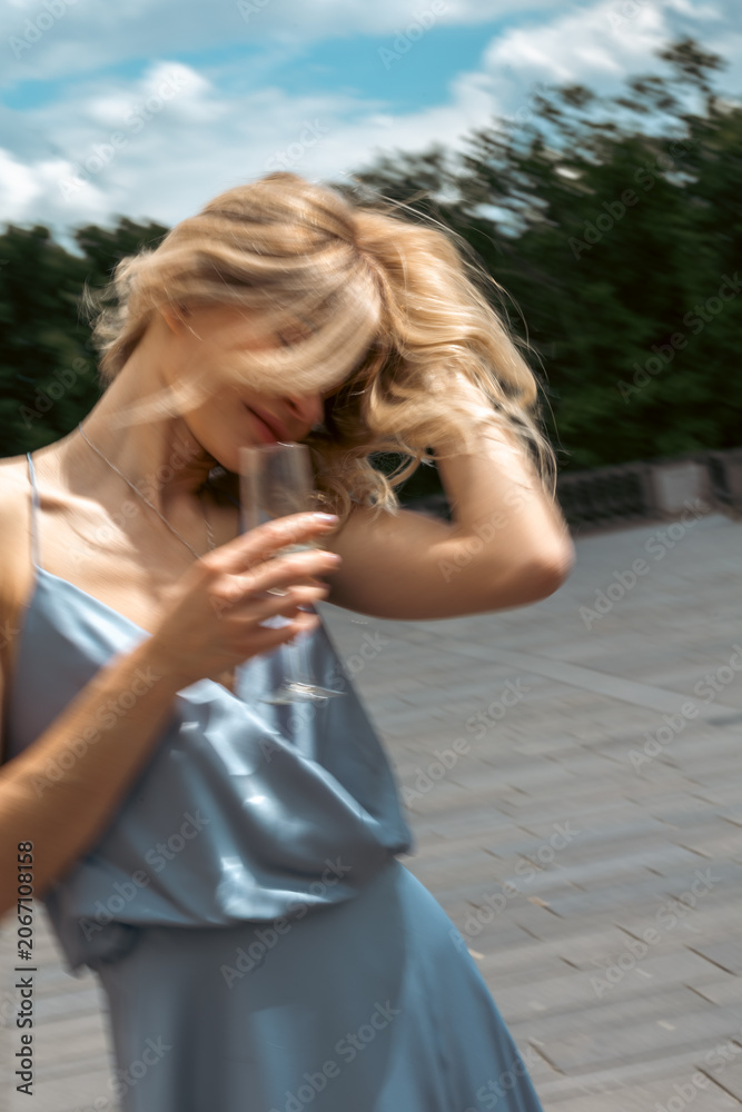 Naklejka premium Woman enjoys a drink outdoors while playing with her hair in a sunny location
