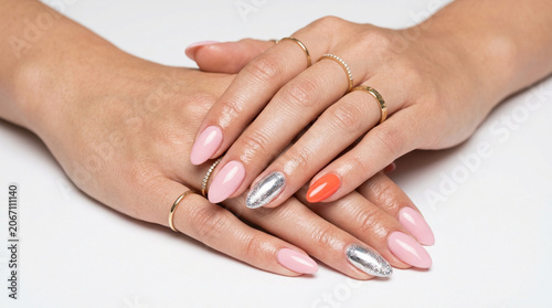 Close up of two hands holding with glossy pale pink almond-shaped nails and silver rings