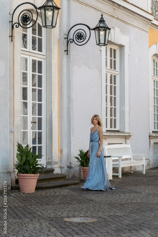 Fototapeta premium Model walks near building with lamps and plants during daytime