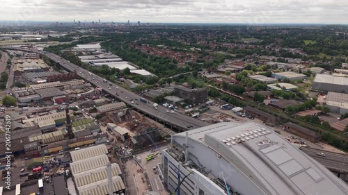 Aerial drone footage showing the M5 motorway passing through industrial estates, residential tower blocks and commercial districts in the West Midlands near Birmingham, England. Urban transport infras