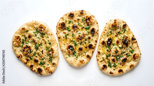 Three pieces of freshly baked garlic naan bread topped with fresh green herbs and oil, traditional indian cuisine flatbread