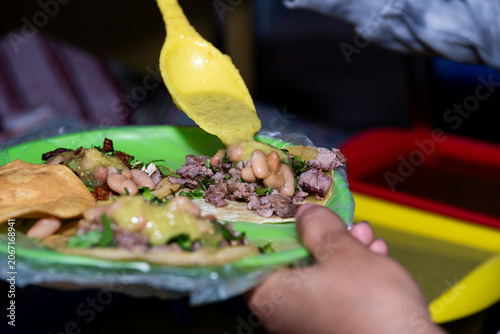 Customer Adding Salsa to Tacos at Mexican Street Food Stand