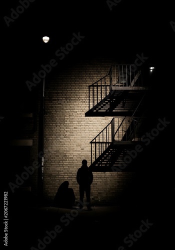 Silhouette of Person Standing Near Fire Escape at Night.