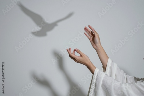 A person in a white robe is reaching out to touch a wall