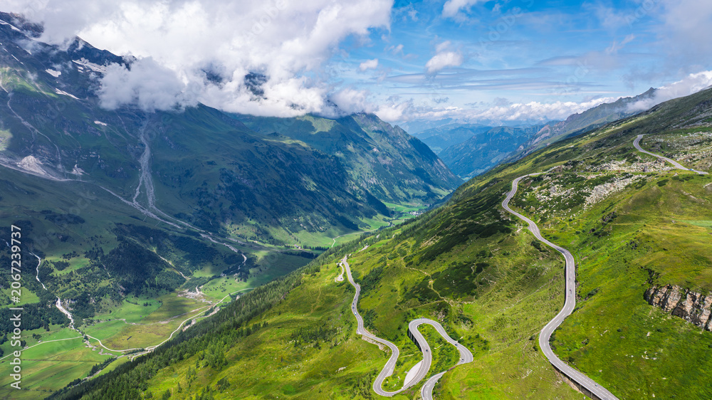 Fototapeta premium Aerial view of the winding Grossglockner High Alpine Road cutting through the green mountain landscape of the Austrian Alps during a bright and sunny summer day in Austria.