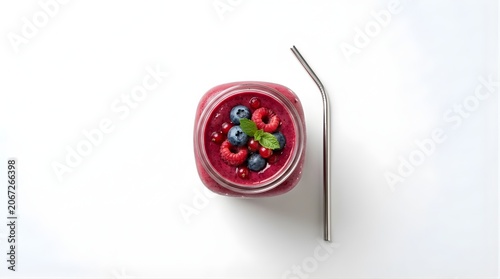Isolated berry smoothie in glass jar with metal straw topped with fresh blueberries raspberries mint healthy lifestyle