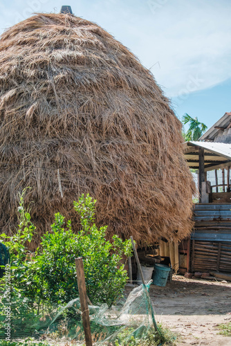 Large traditional haystack next to rustic outbuildings in a rural yard