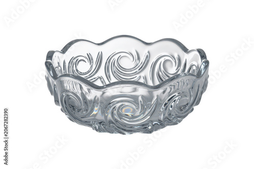 A clear glass bowl with an intricate swirling circular pattern on its outer surface, isolated on a solid black background, for clear viewing