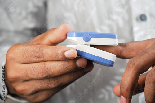 Canvas-taulu a person using a white and blue fingertip pulse oximeter