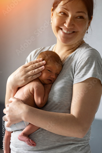 Mother holding her crying newborn with tender affection, celebrating motherhood and family connection during infancy, expressing care and warmth