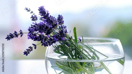 Lavender sprigs in a glass of water, with a blurred background